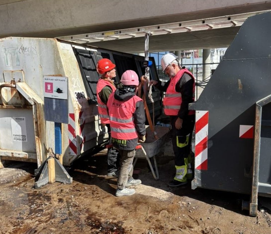 Ressourcekoordinatorer i pink hjelme ved containerne